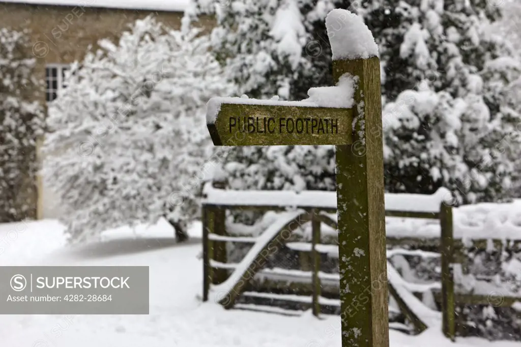 England, Gloucestershire, South Cerney. Snow on top of a Public Footpath sign in a snowy winter village.