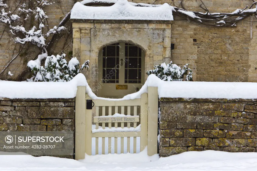 England, Gloucestershire, South Cerney. Snow covered gate and path leading to the front door of Silver Street House, a stone built Cotswold village house in South Cerney.