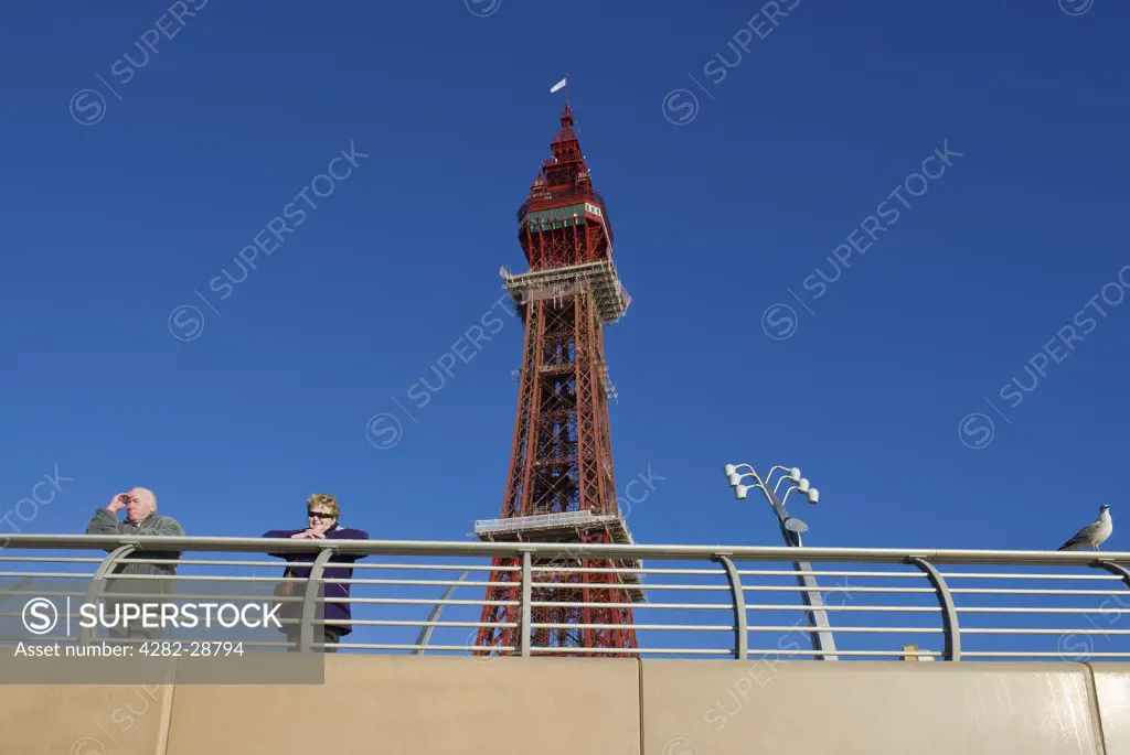 England, Lancashire, Blackpool. Holidaymakers on the promenade with the Blackpool Tower in the background.