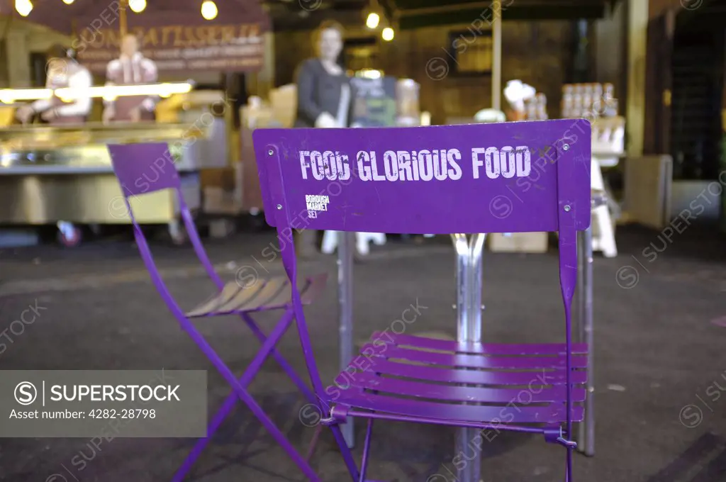England, London, Borough. Food Glorious Food written on the back of a chair by a cafe table at Borough Market.
