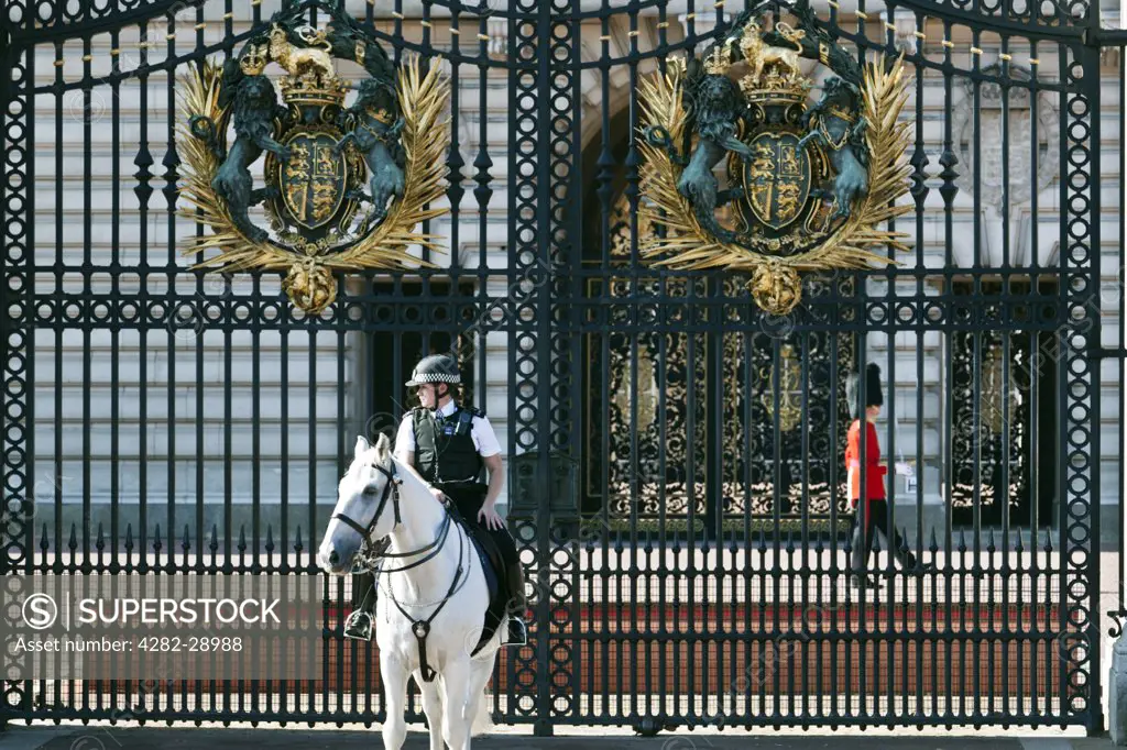 England, London, Buckingham Palace. A mounted police officer and a Queen's Guard on duty outside Buckingham Palace.