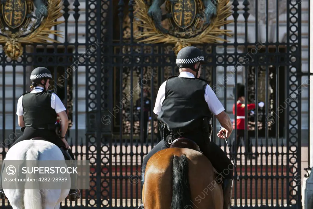 England, London, Buckingham Palace. Mounted police officers and a Queen's Guard on duty outside Buckingham Palace.