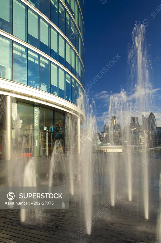 England, London, Southwark. Water fountains near City Hall and the 'More London' development on the south bank of the River Thames, looking towards the landmark skyscrapers of the City of London.