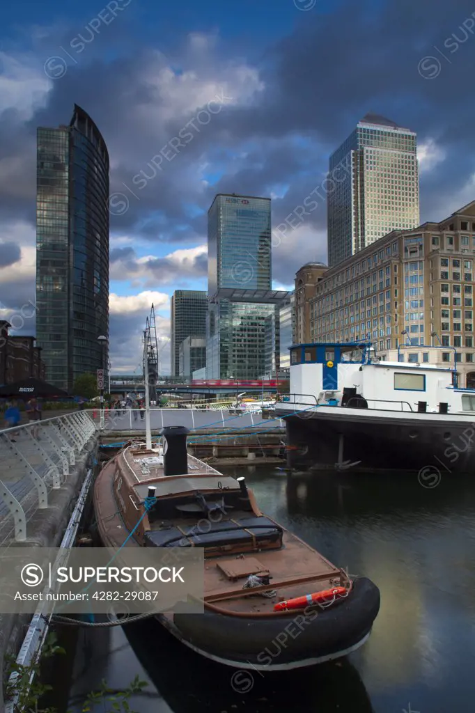 England, London, West India Quay. Boats in West India Quay with skyscrapers (amongst the tallest buildings in the UK) in Canada Square in the background.