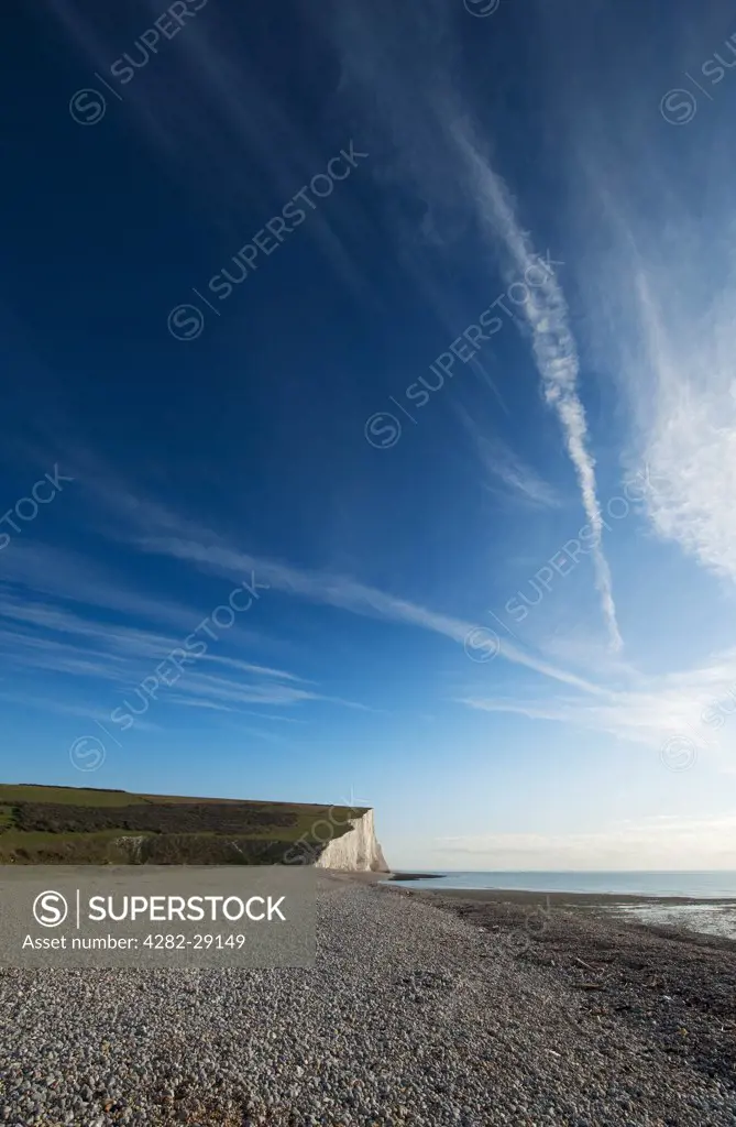 England, East Sussex, Cuckmere Haven. Shingle bank and vertical chalk sea cliffs at Cuckmere Haven.