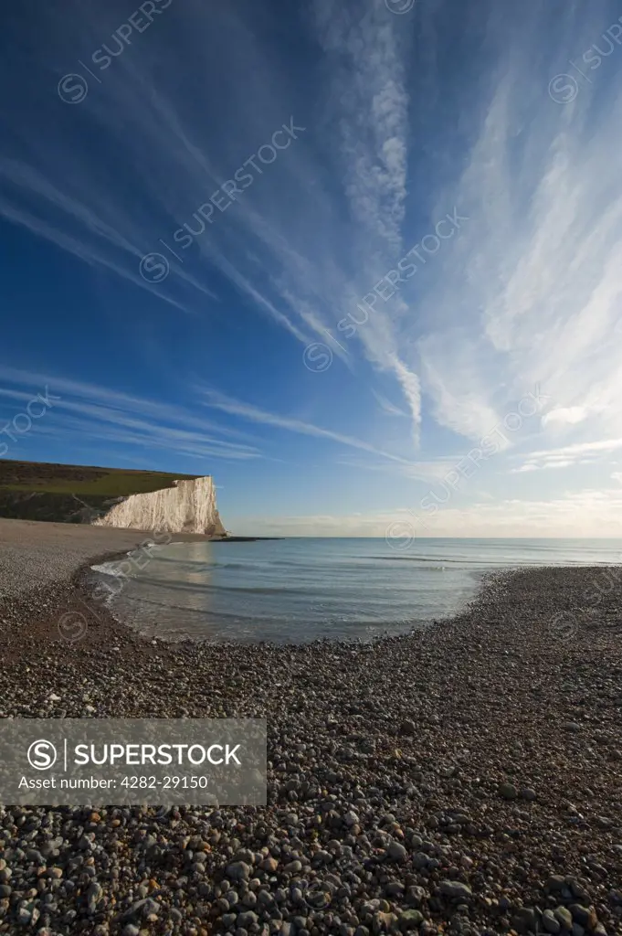 England, East Sussex, Cuckmere Haven. Shingle bank and vertical chalk sea cliffs at Cuckmere Haven.