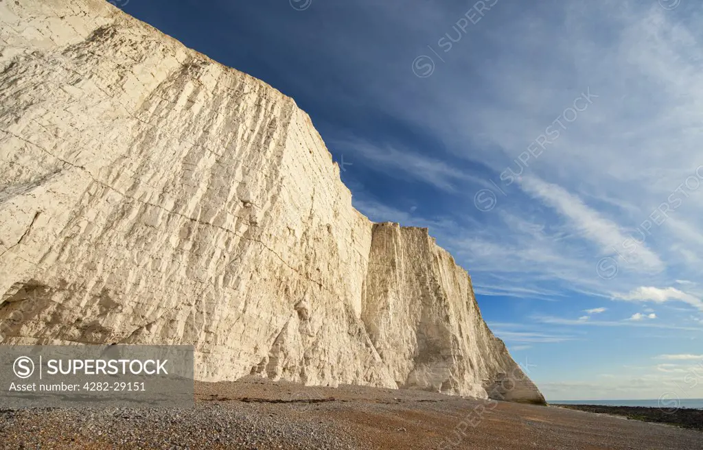 England, East Sussex, Cuckmere Haven. Shingle beach under vertical stratified chalk sea cliffs at Cuckmere Haven.