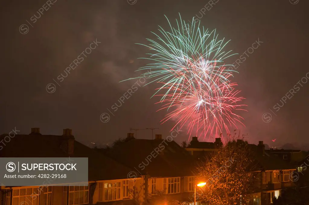 England, London. Evening firework display above houses in the suburbs of London on Guy Fawkes night (bonfire night), celebrated annually on the 5th November.
