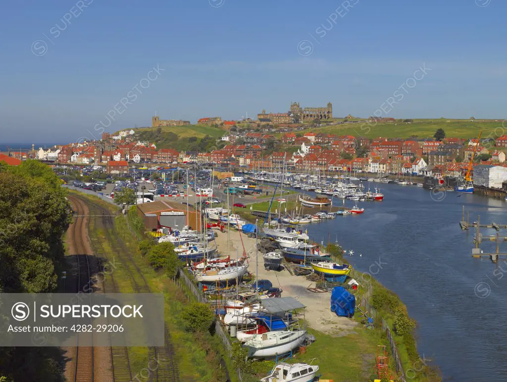 England, North Yorkshire, Whitby. Railway tracks running alongside boats moored on the River Esk at Whitby.