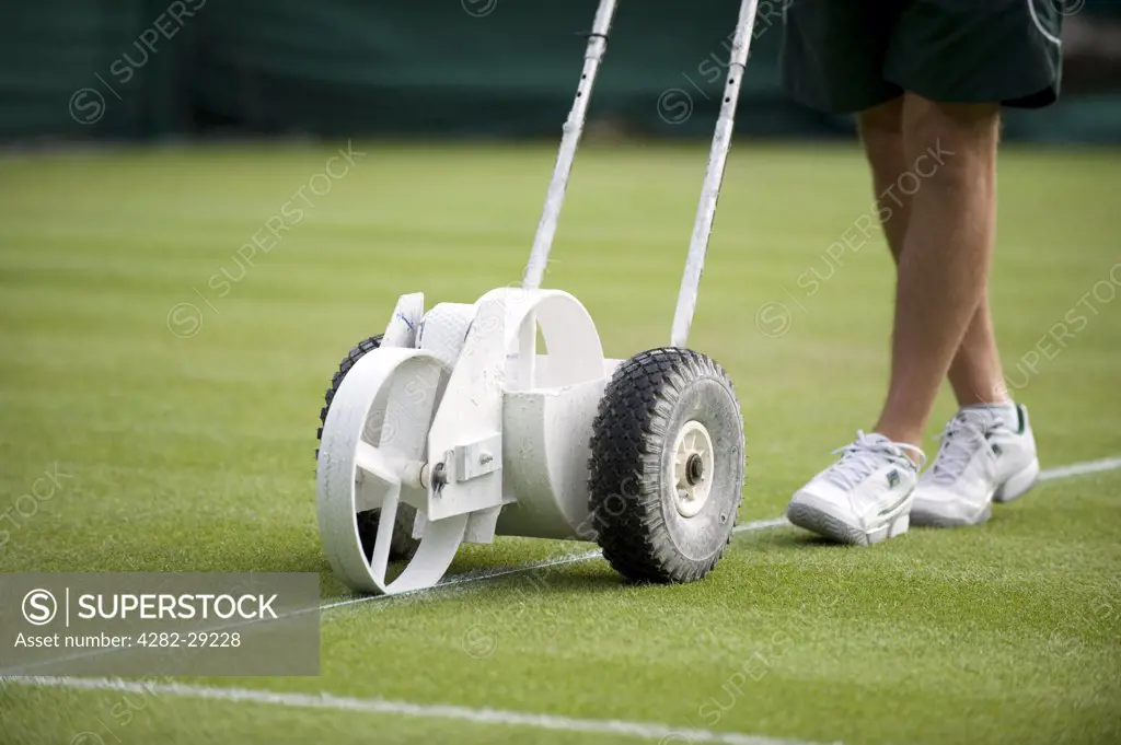 England, London, Wimbledon. Groundsman painting the white lines on court 4 during the 2011 Wimbledon Tennis Championships.