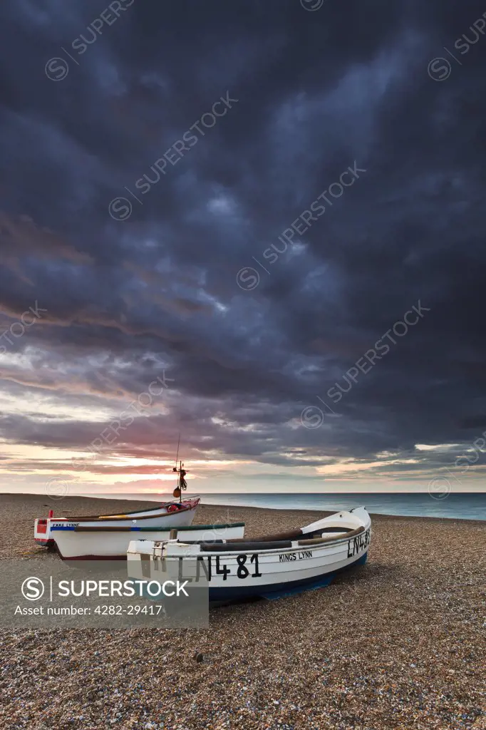 England, Norfolk, Cley next the Sea. Three small fishing boats on the shingle beach of Cley next the Sea on the North Norfolk coast.