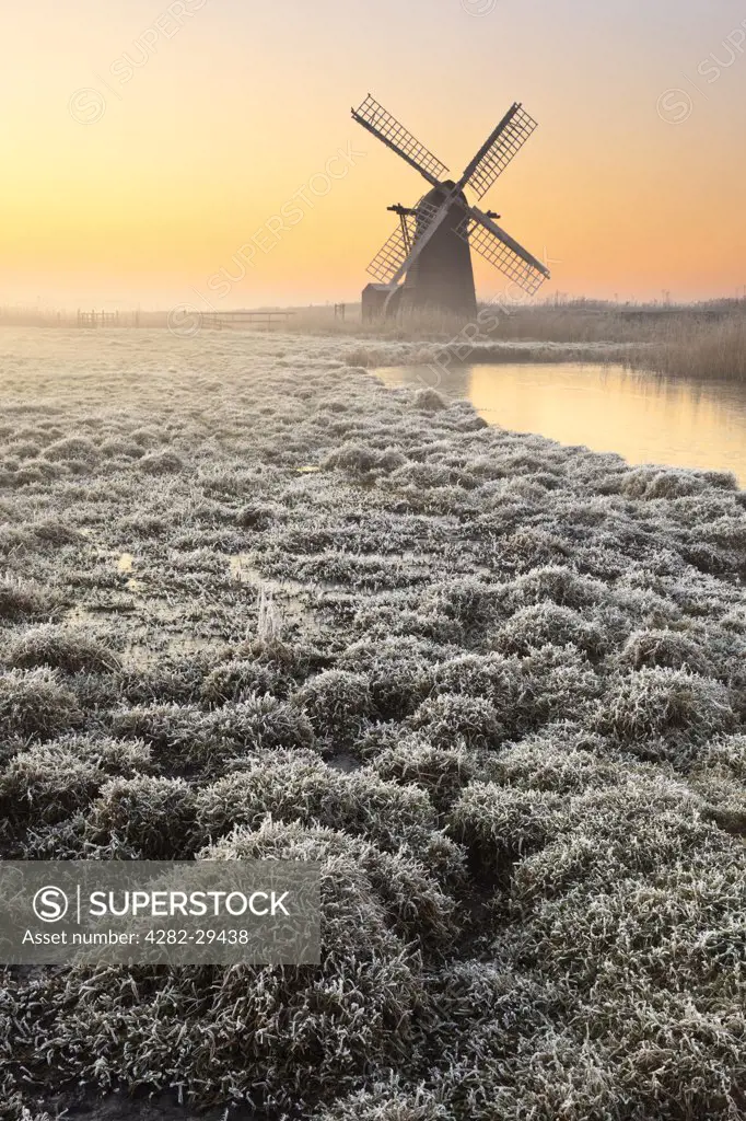 England, Suffolk, Herringfleet. View over frosty ground to Herringfleet smock mill in the mist on a winter morning.