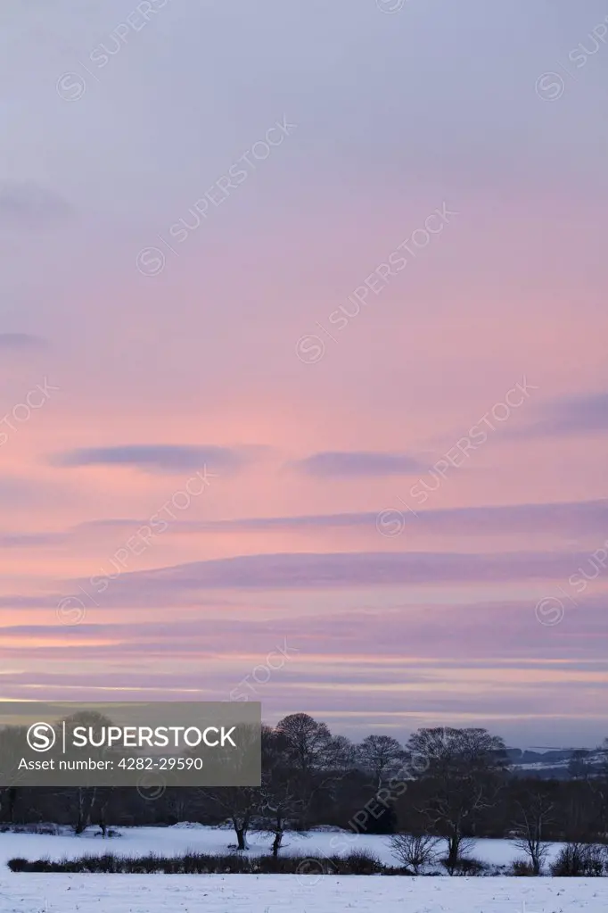 England, County Durham, Durham. A pink evening winter sky over a snow covered field.