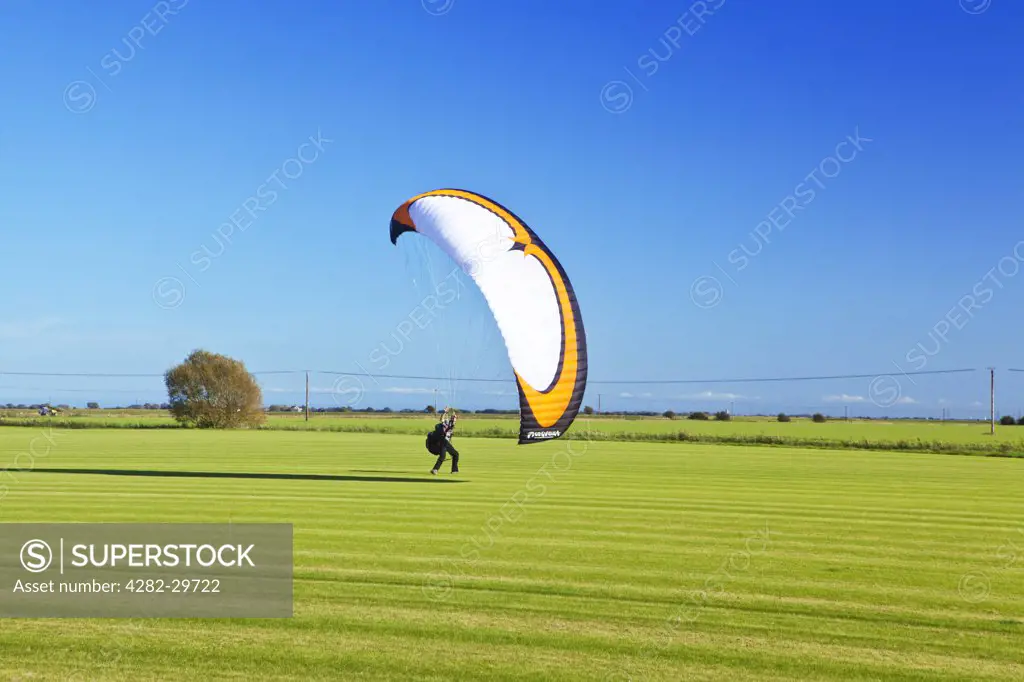 England, Kent, Romney. A parachutist landing in a field near Romney Marsh.