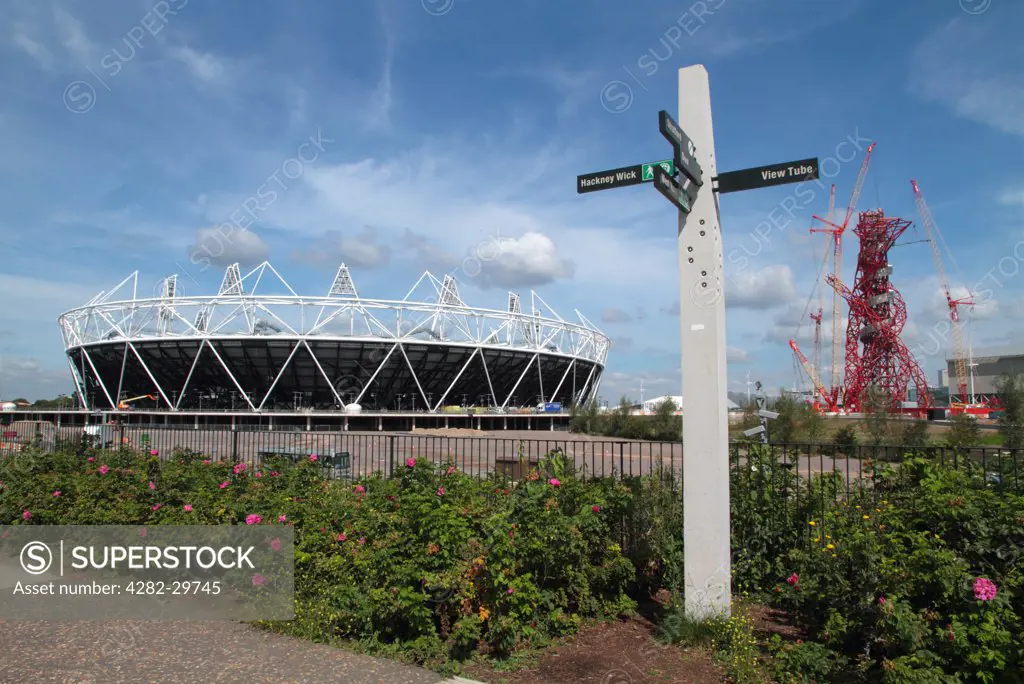 England, London, Stratford. The London 2012 Olympic stadium, the ArcelorMittal Orbit observation tower and signpost in the Olympic Park.