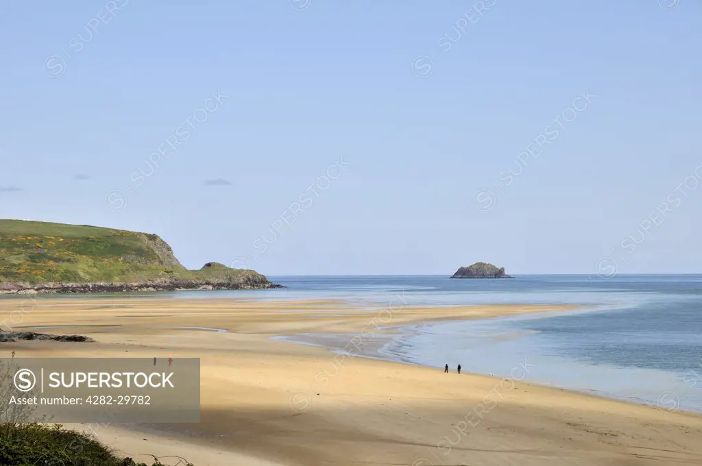 England, Cornwall, Hawker's Cove. People walking on the sandy beach at Hawker's Cove on the River Camel estuary.