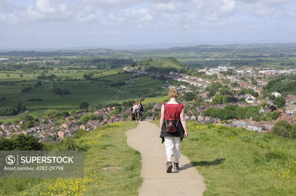 England, Somerset, Glastonbury. Walkers on a path leading down from Glastonbury Tor towards the town.