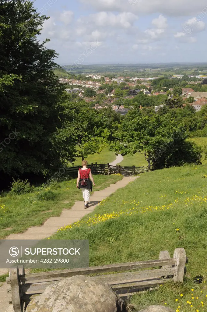 England, Somerset, Glastonbury. A woman walking down a path leading from Glastonbury Tor towards the town.