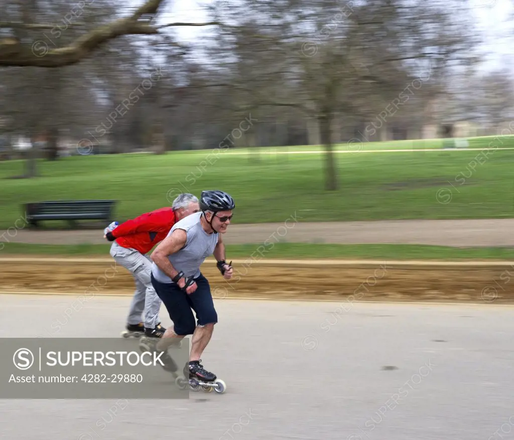 England, London, Hyde Park. Two men skating at speed through Hyde Park.