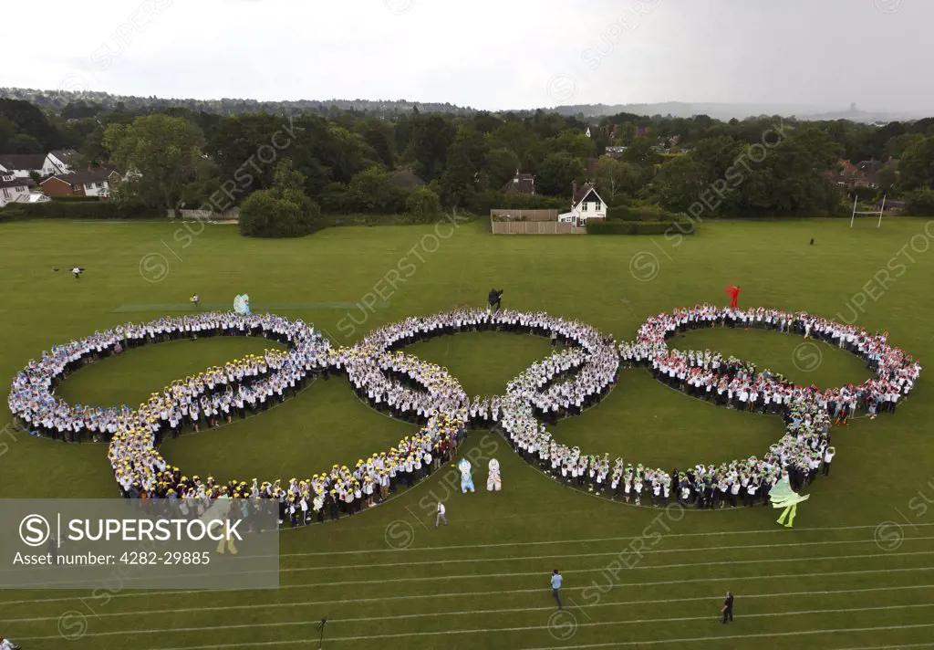 England, Surrey, Guildford. Elevated view of world record to form the largest human Olympic Rings symbol, comprising 1,900 school children and staff at George Abbot School, Guildford.