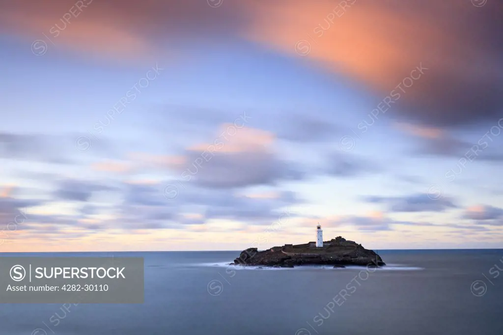 England, Cornwall, Godrevy. Sunset over Godrevy lighthouse, built in the mid 19th century to warn shipping of the danger of a submerged reef known as the Stones.