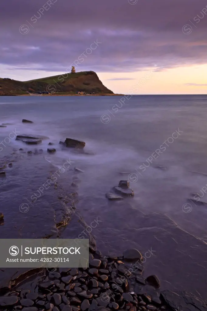 England, Dorset, Kimmeridge Bay. View over rocky ledges in Kimmeridge Bay towards Clavell Tower, a Tuscan style tower built in 1830 on Hen cliff on the Jurassic Coast in the Isle of Purbeck.