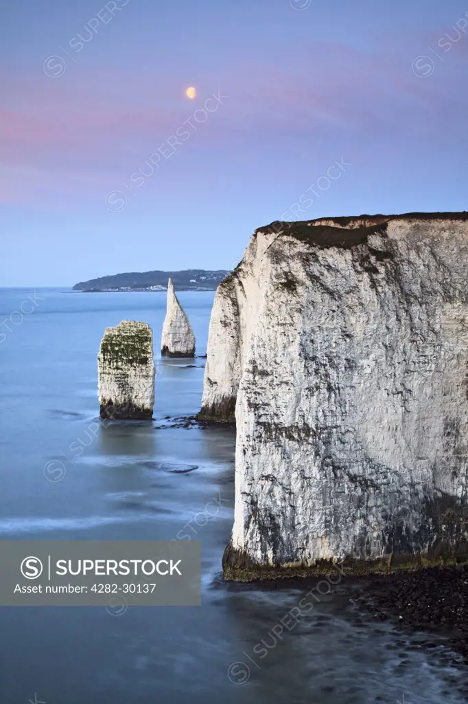 England, Dorset, Swanage. The moon setting over the Pinnacles, at Handfast Point near Swanage.