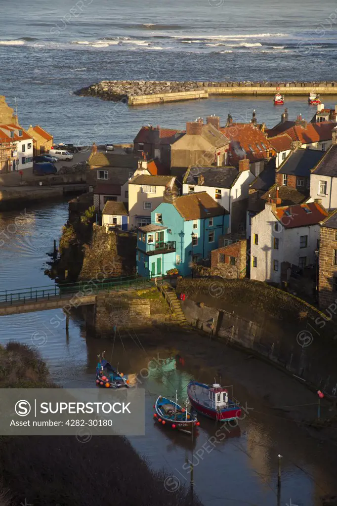 England, North Yorkshire, Staithes. Fishing boats in the sheltered harbour at Staithes at dusk.