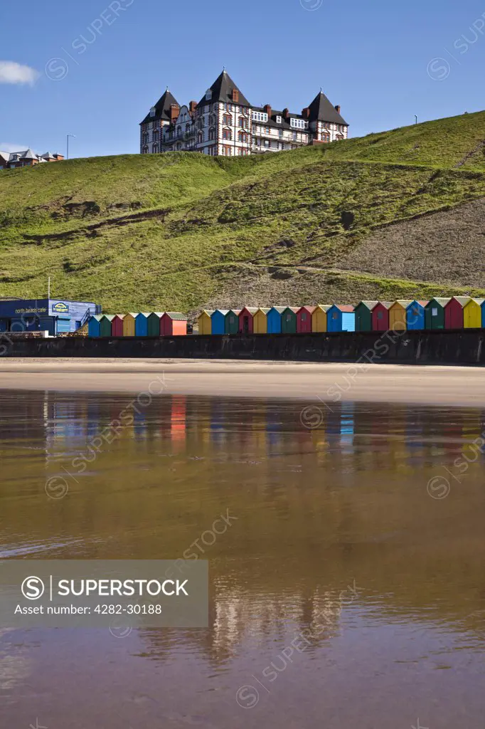 England, North Yorkshire, Whitby. Colourful beach huts along West Cliff Beach in Whitby.