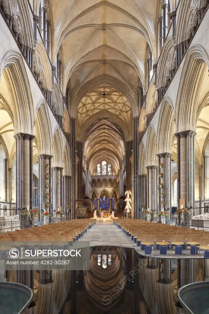 England, Wiltshire, Salisbury. View of Nave and Christmas nativity scene in Salisbury Cathedral with the ceiling reflected in water in the font.