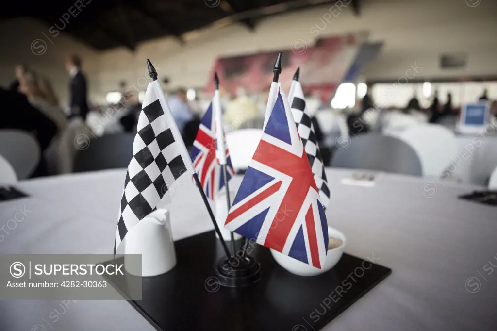 England, Northamptonshire, Silverstone. Union and chequered flags in the centre of a table in the VIP Wing at Silverstone.