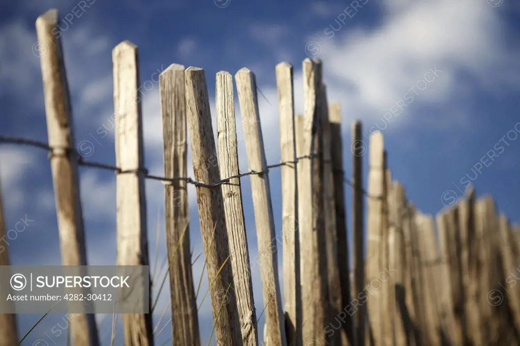 England, Devon, Bantham. Wooden fence posts marking a path through sand dunes at Bantham Beach.