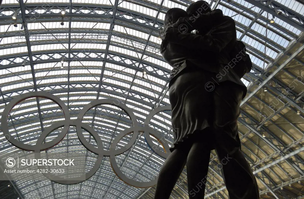 England, London, King's Cross. The Lovers statue, a 20-tonne bronze sculpture by Paul Day and a giant set of Olympic rings in St Pancras International.