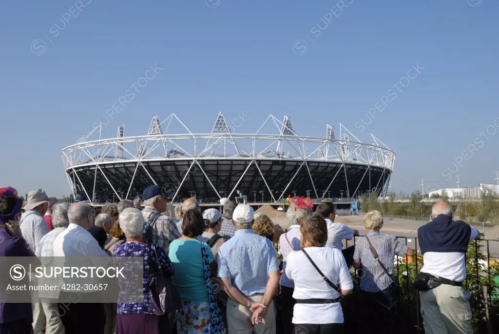 England, London, Stratford. Tourists viewing the Olympic Stadium in Olympic Park.