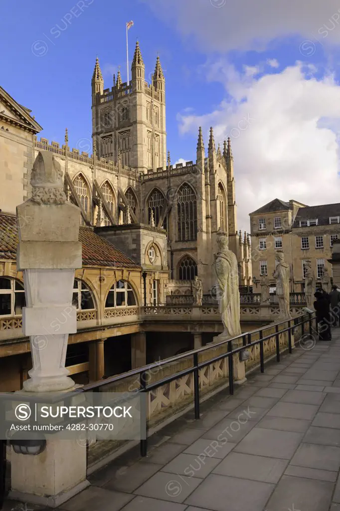 England, Bath and North East Somerset, Bath. Roman statues around the Roman Baths with Bath Abbey in the background.