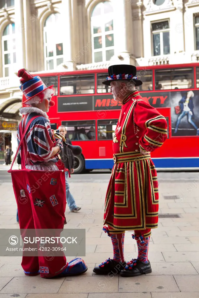 England, London, Bond Street. Two people in British themed costumes pose with a red bus in the background.