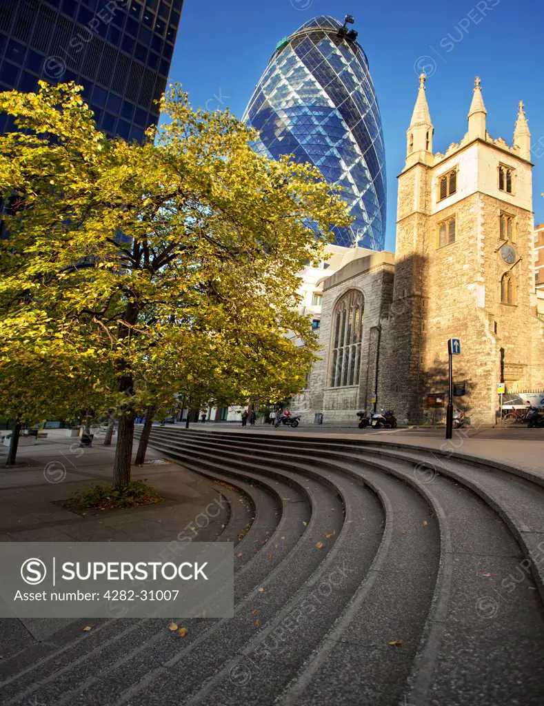 England, London, City of London. A view of the Swiss Re tower and St Andrew Undershaft church beneath it.