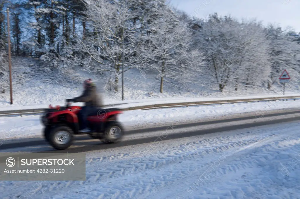 England, Worcestershire, Worcester. A quad bike driving through snow outside Worcester.