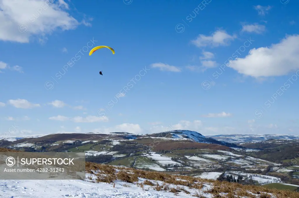 Wales, Powys, Wye Valley. A paraglider soars along a ridge in the Wye Valley.