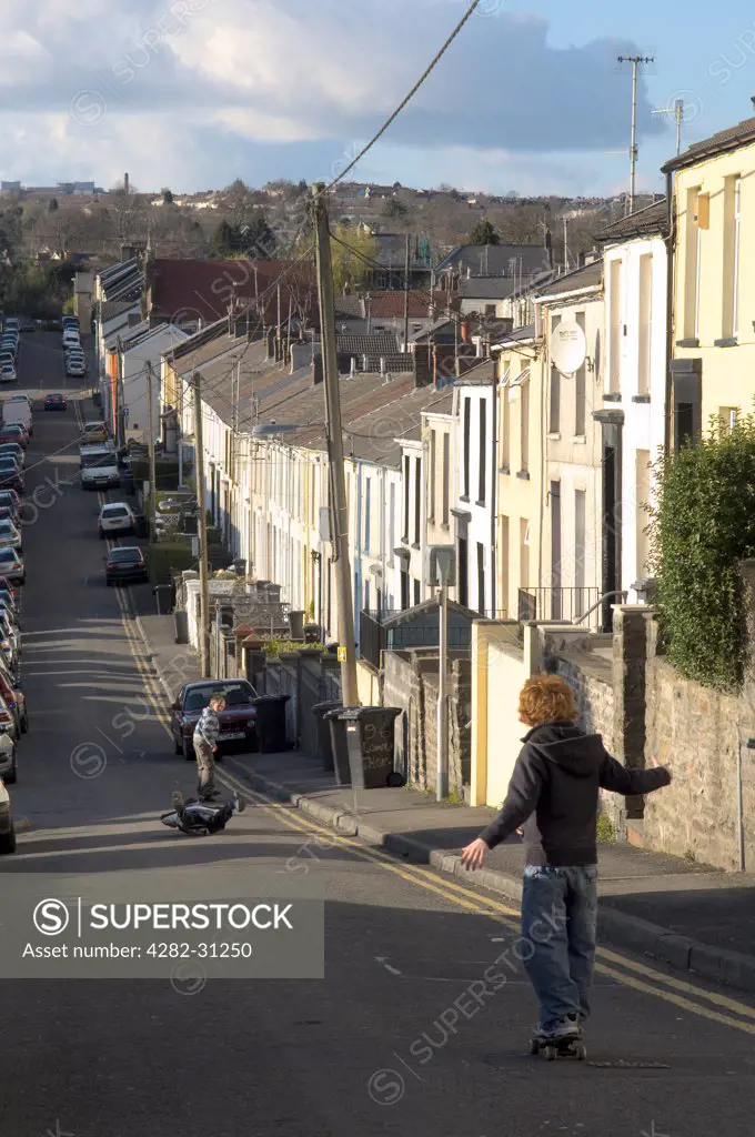 Wales, Glamorgan, Merthyr Tydfil. Children skateboard along a street in Merthyr Tydfil in Wales.