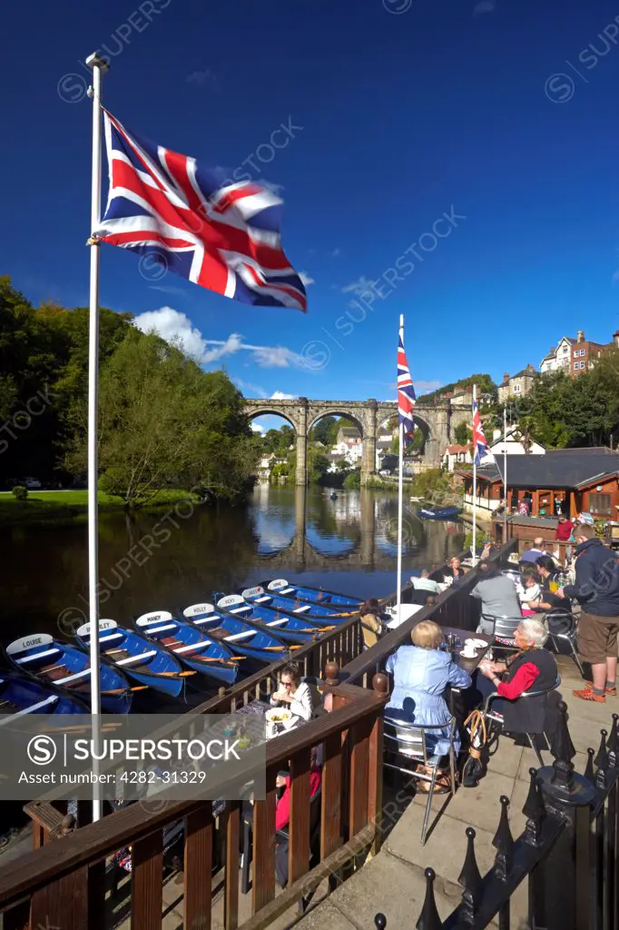 England, North Yorkshire, Knaresborough. A view of the River Nidd from the riverside cafe with the Victorian railway viaduct reflected in the waters below.