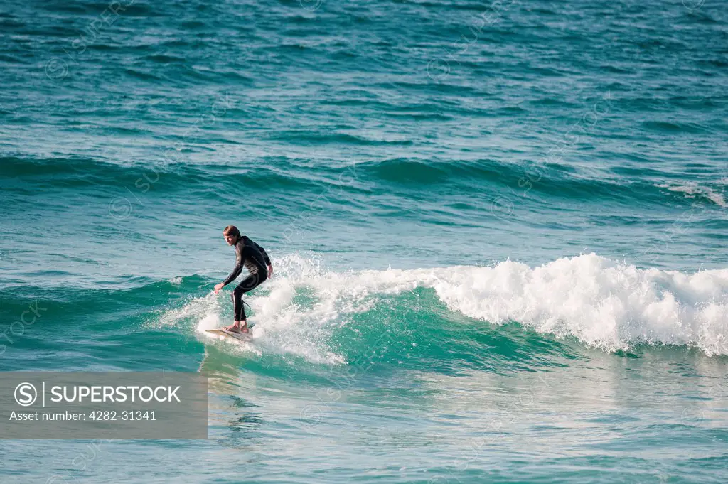 England, Cornwall, Sennen. A surfer at Sennen Cove.