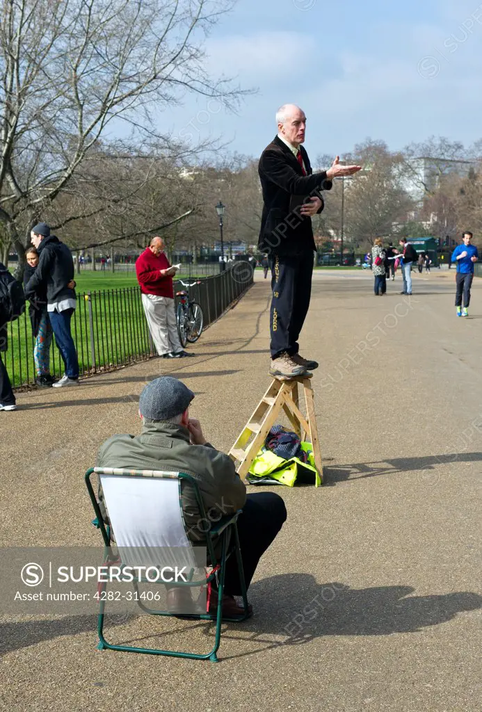 England, London, Hyde Park. A man sitting in a chair listening to a speaker at Speakers Corner in London.