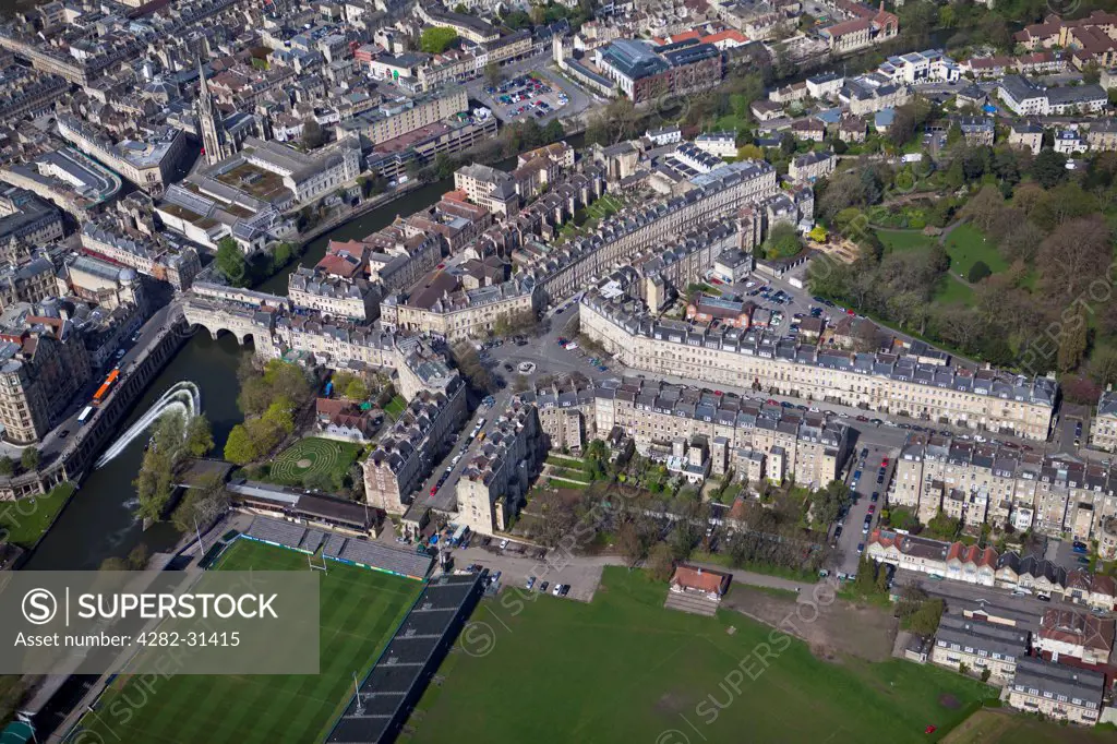 England, Bath and North East Somerset, Bath. An aerial view of historic Bath with Pulteney Bridge spanning the River Avon and Bath Rugby Club at bottom left.