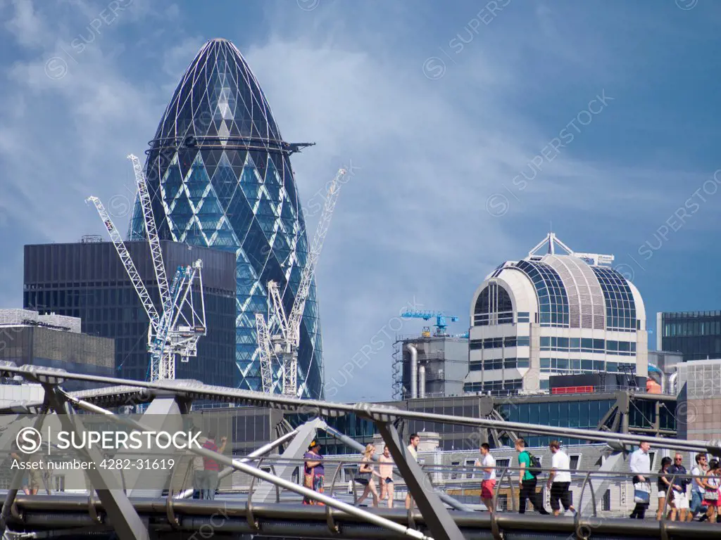 England, London, The Gherkin. The Gherkin and cranes with the Millennium Bridge in the foreground.