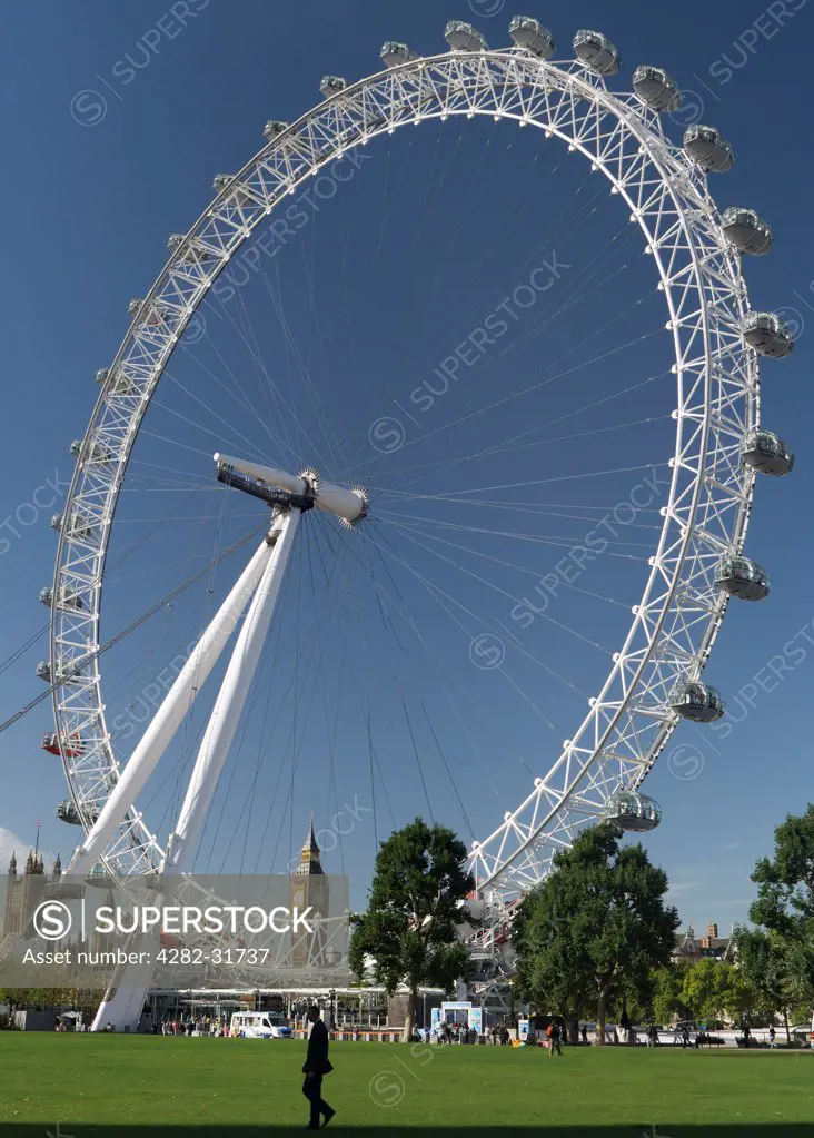 England, London, South Bank. A man walking in Jubilee Gardens with a backdrop of the London Eye.