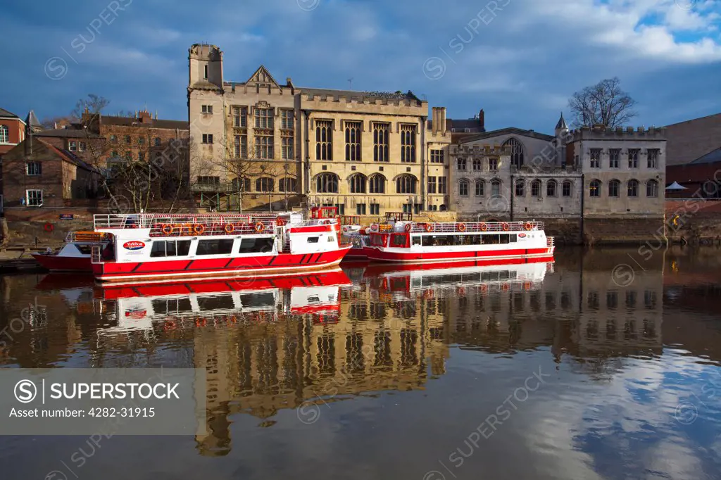 England, North Yorkshire, York City. York city river cruise boats moored on the River Ouse with the Guildhall in the background.