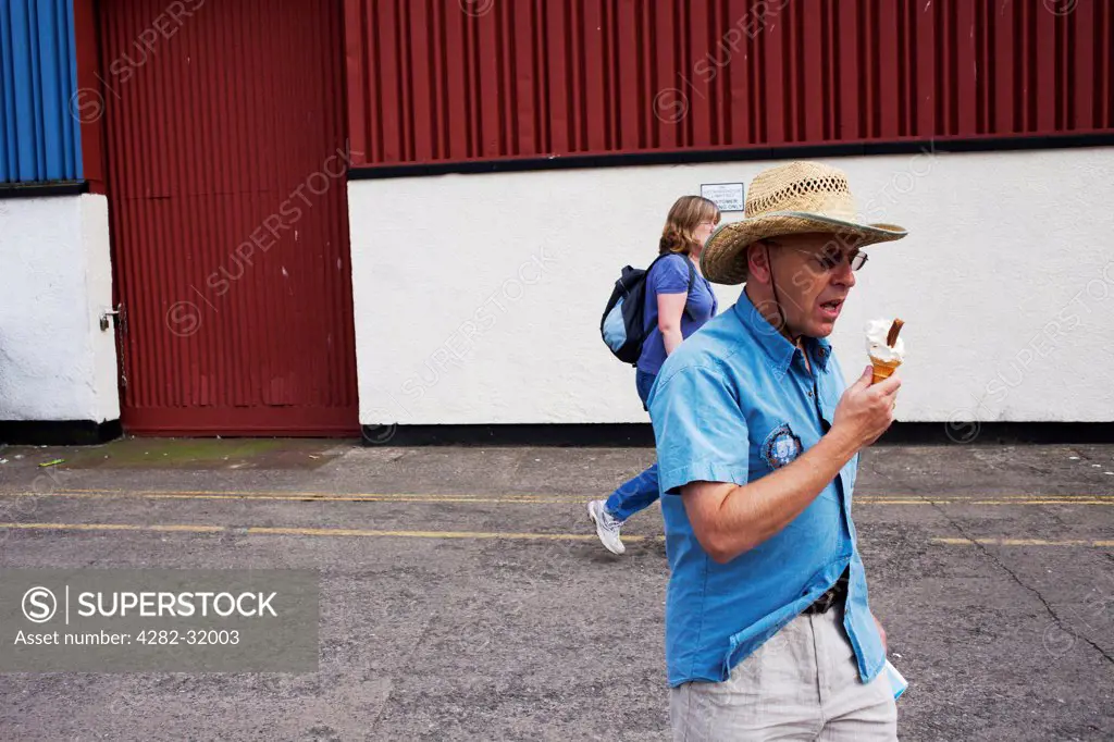 England, Bristol, Harbourside. A man eating an ice cream at Harbourside in Bristol.
