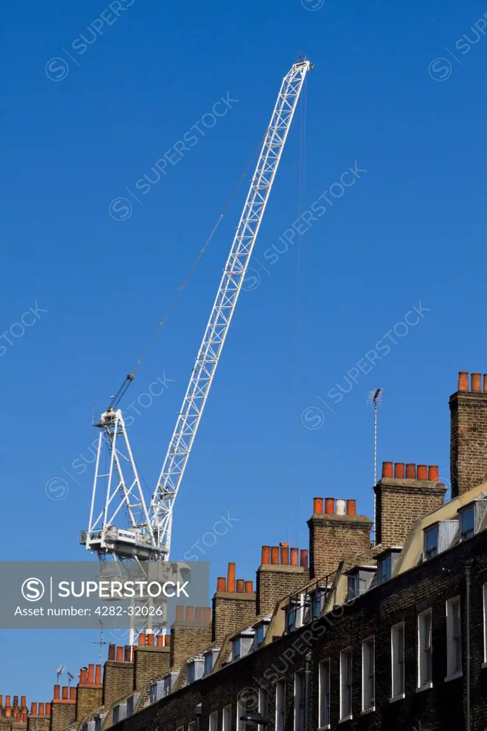England, London, Pimlico. A crane towers above a row of Victorian houses.