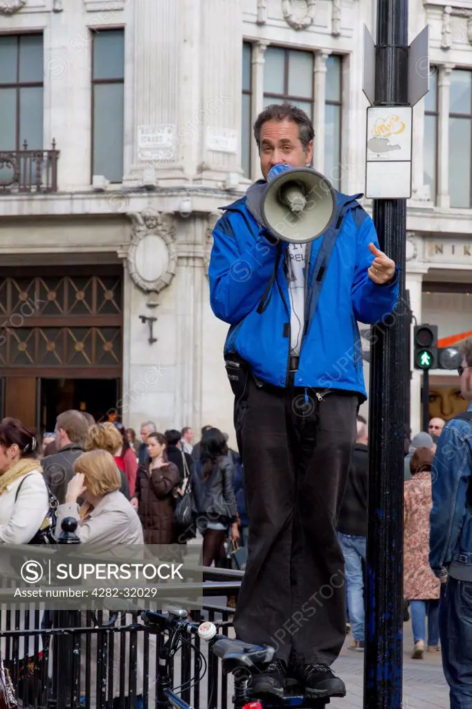 England, London, Oxford Circus. A man standing on a post addressing indifferent crowds of people in Oxford Circus.